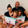 Mamá, papá y sus tres hijos están leyendo su libro personalizado para familias y disfrutando de pasar tiempo juntos.